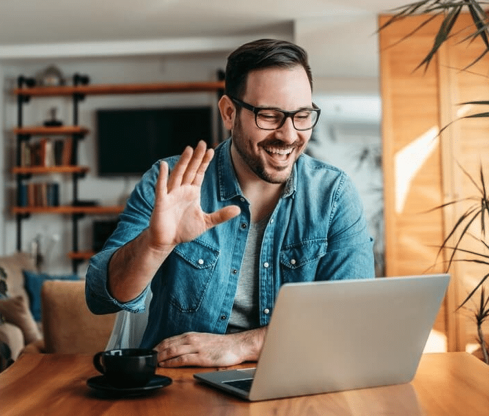 man waving at laptop smiling during online therapy group | Kindful Body | Online Eating Disorder Therapists and Nutrition Counselors | San Francisco, CA 94115 and San Carlos, CA 94070